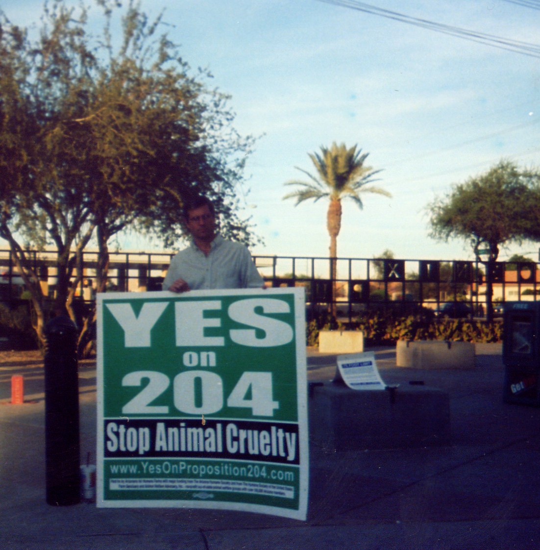Farm Sanctuary President and Co-founder Gene Baur stands with a sign saying "Yes on 204"