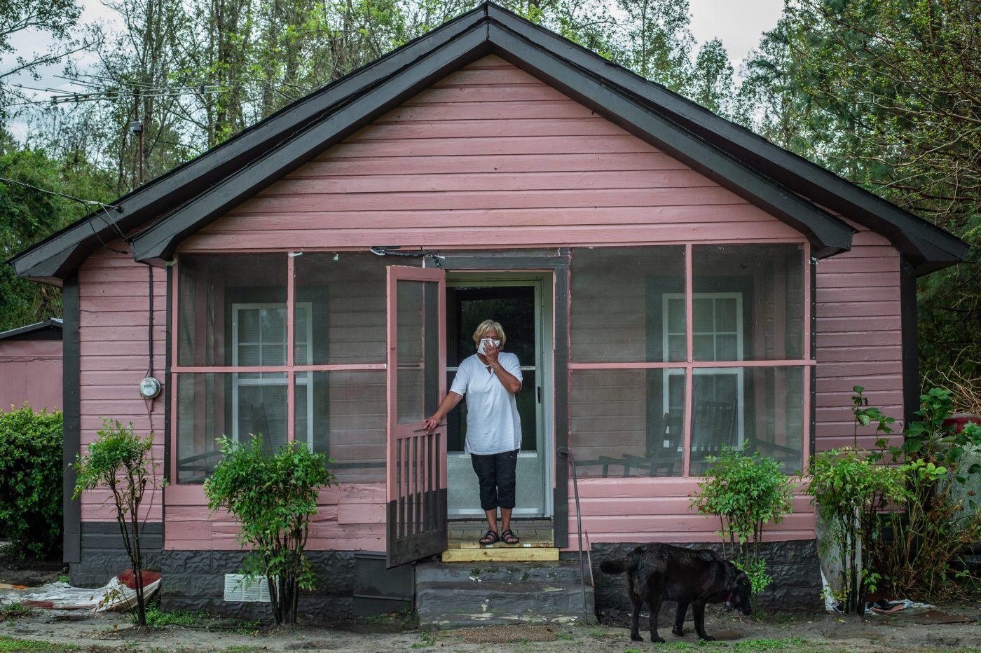 Activist Elsie Herring, stands on the porch of her family home, holding a handkerchief over her mouth to filter out manure being sprayed on the field next door / Photo Credit: Jo-Anne McArthur / We Animals