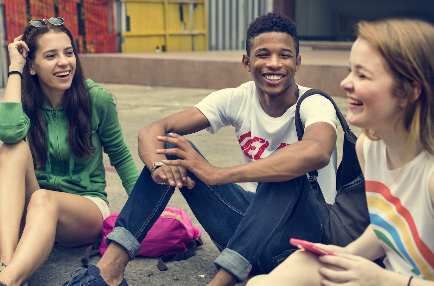 Three teenagers sitting and talking while smiling